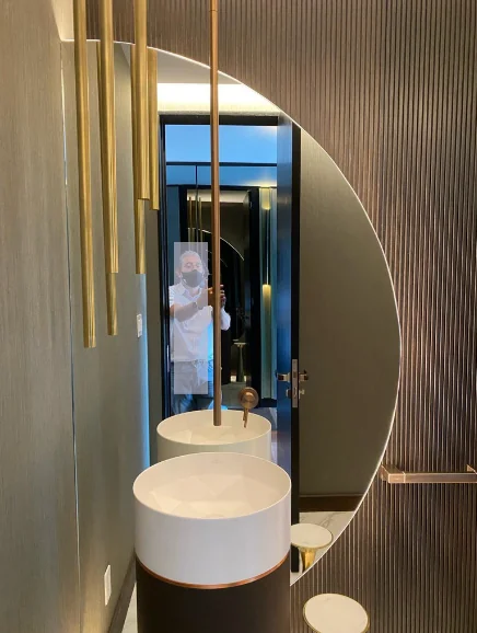 Espejo semicircular de diseño sobre lambrín acanalado y lavamanos de pedestal