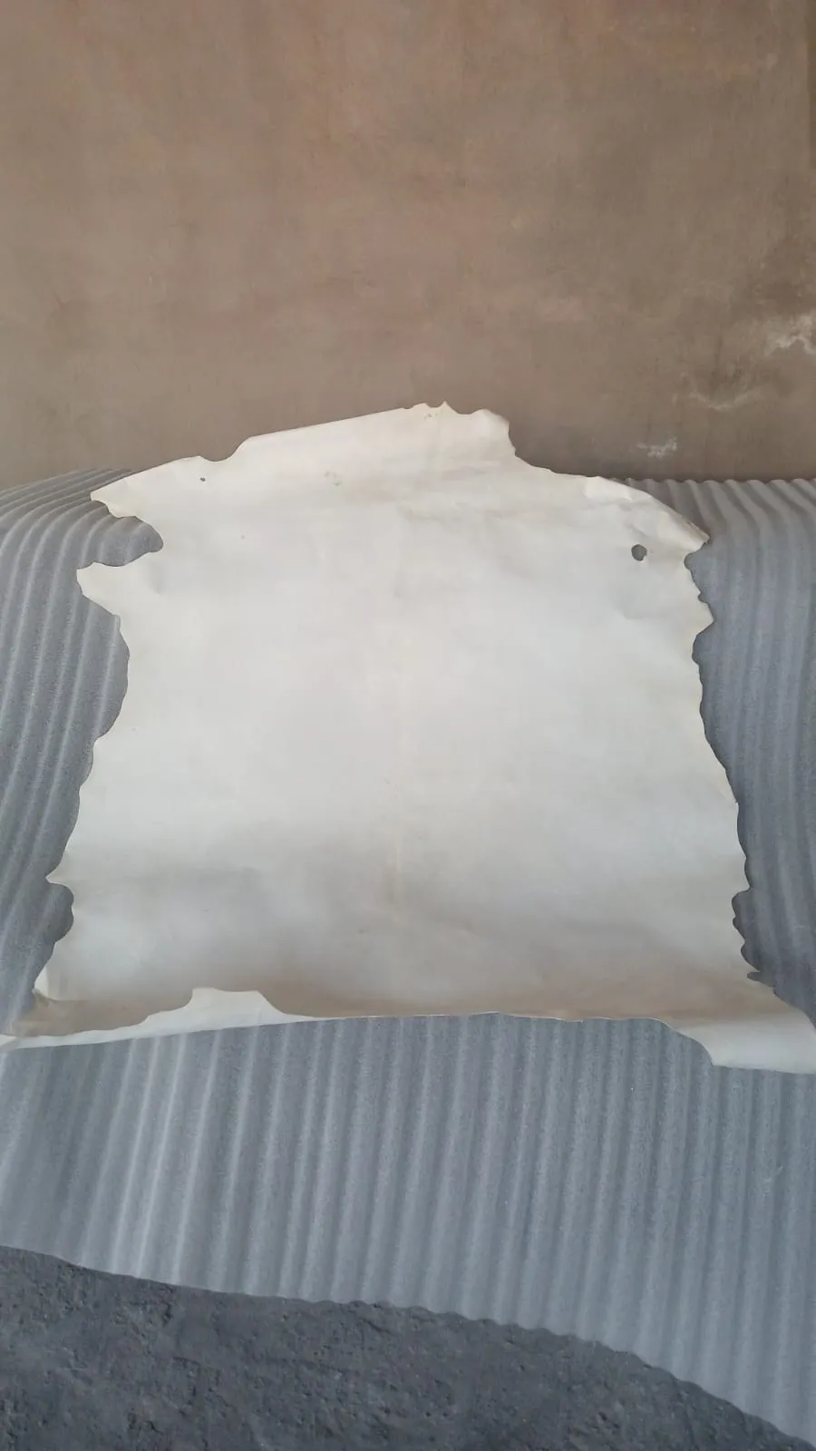 Proceso de aplicación manual de piel de cabra sobre mesa de centro en taller